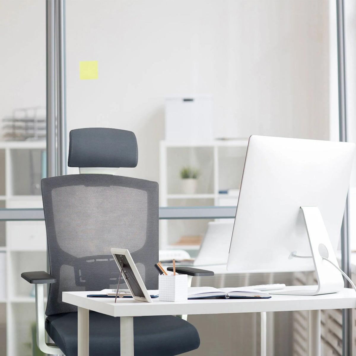 Grijze Professionele bureaustoel CAPTIVO BASE W met netrugleuning en hoofdsteun aan een bureau van hjh OFFICE