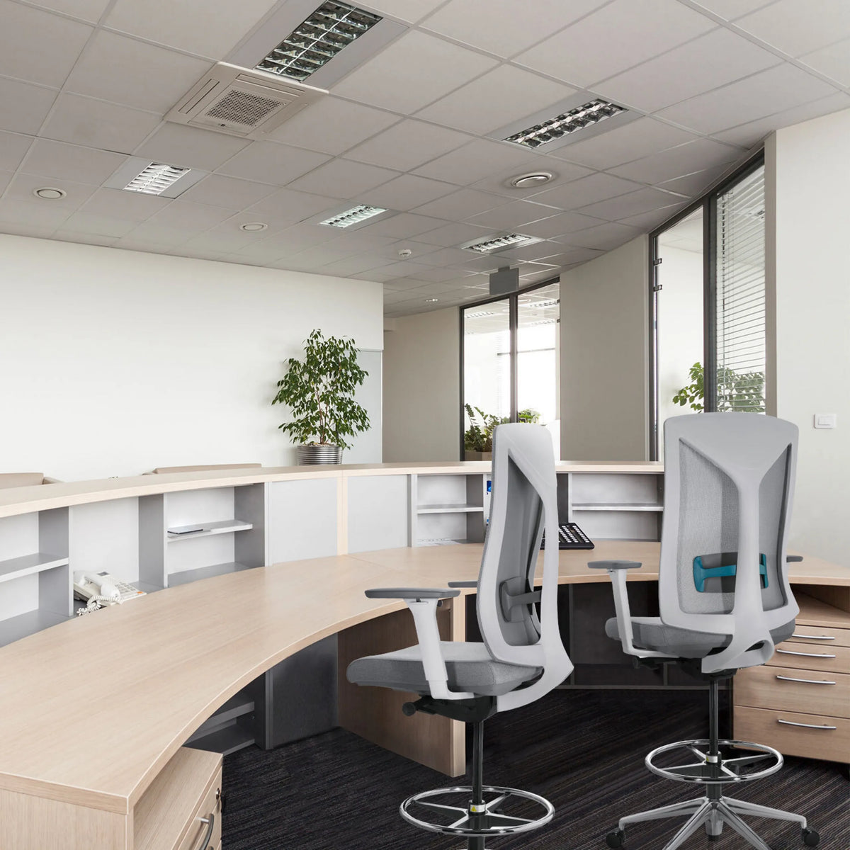 Twee grijze HALIFAX WORK baliestoelen met netrugleuning en voetringen aan een gebogen bureau van hjh OFFICE