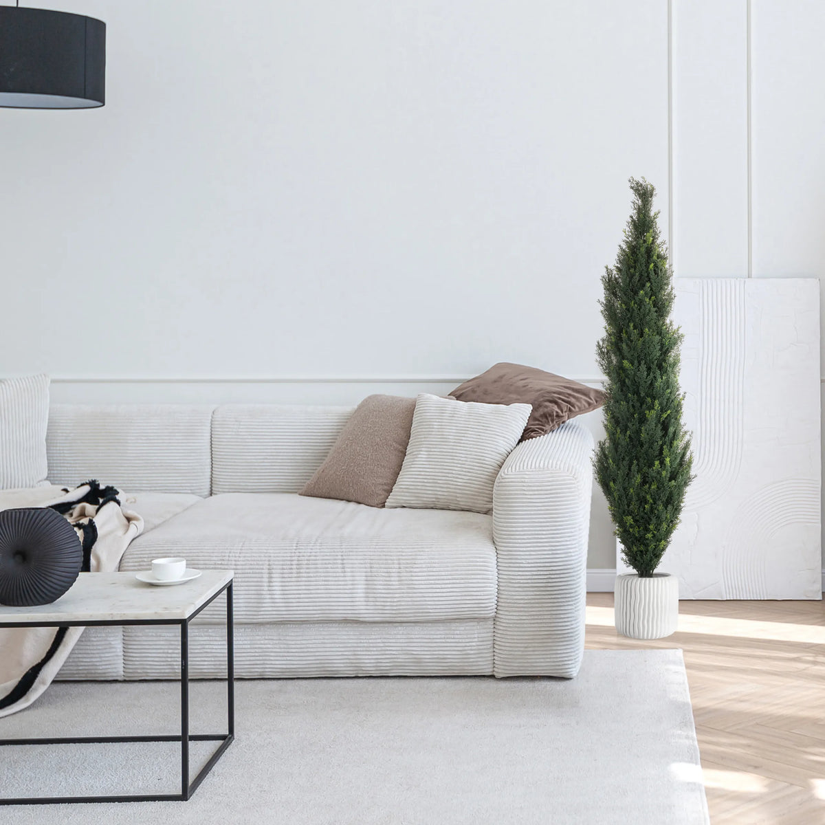 Groene kunstplant CEDRUS in een witte pot naast een witte bank van hjh OFFICE