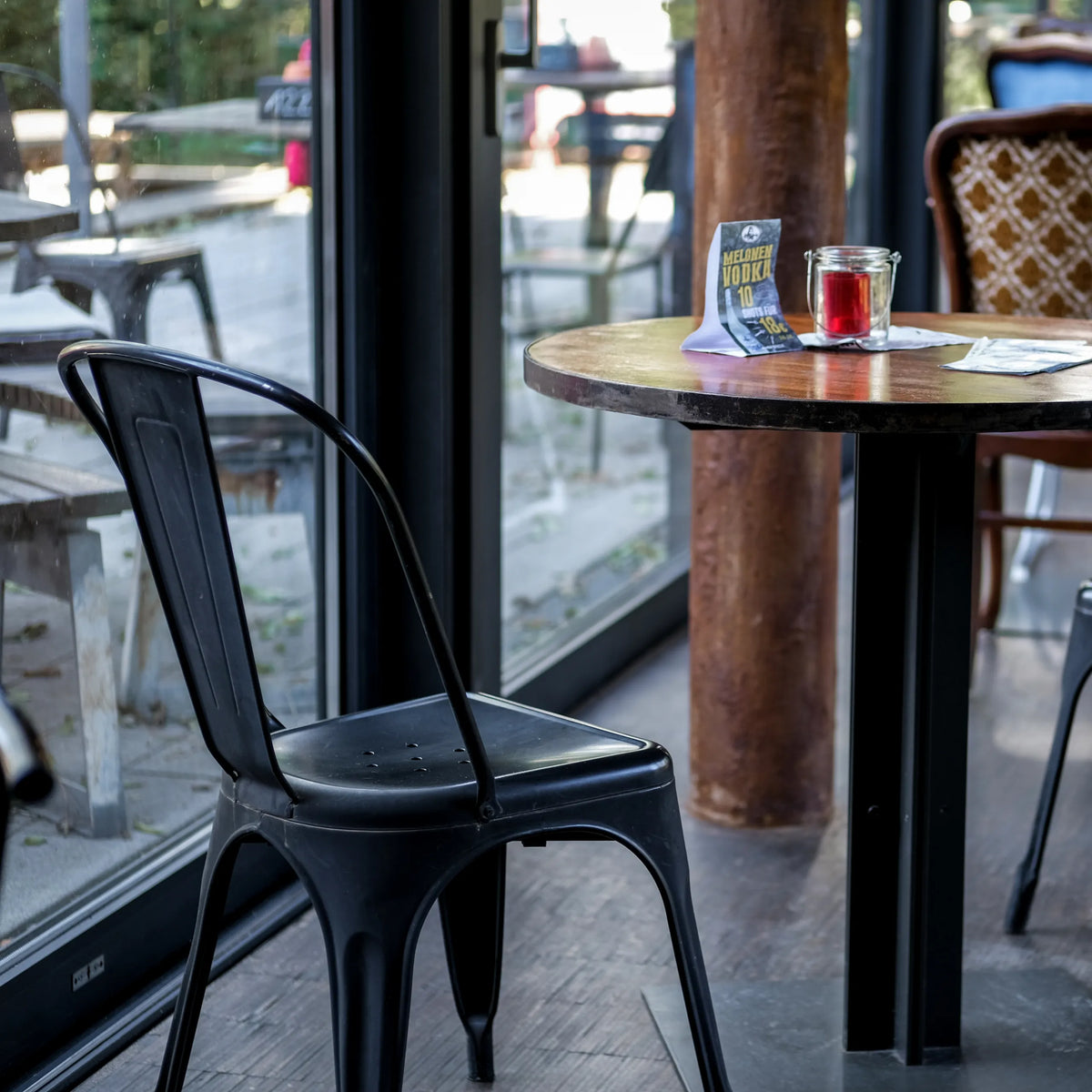 Zwarte Bistrostoel VANTAGGIO BRUSH met gebogen rugleuning aan een ronde tafel van hjh OFFICE