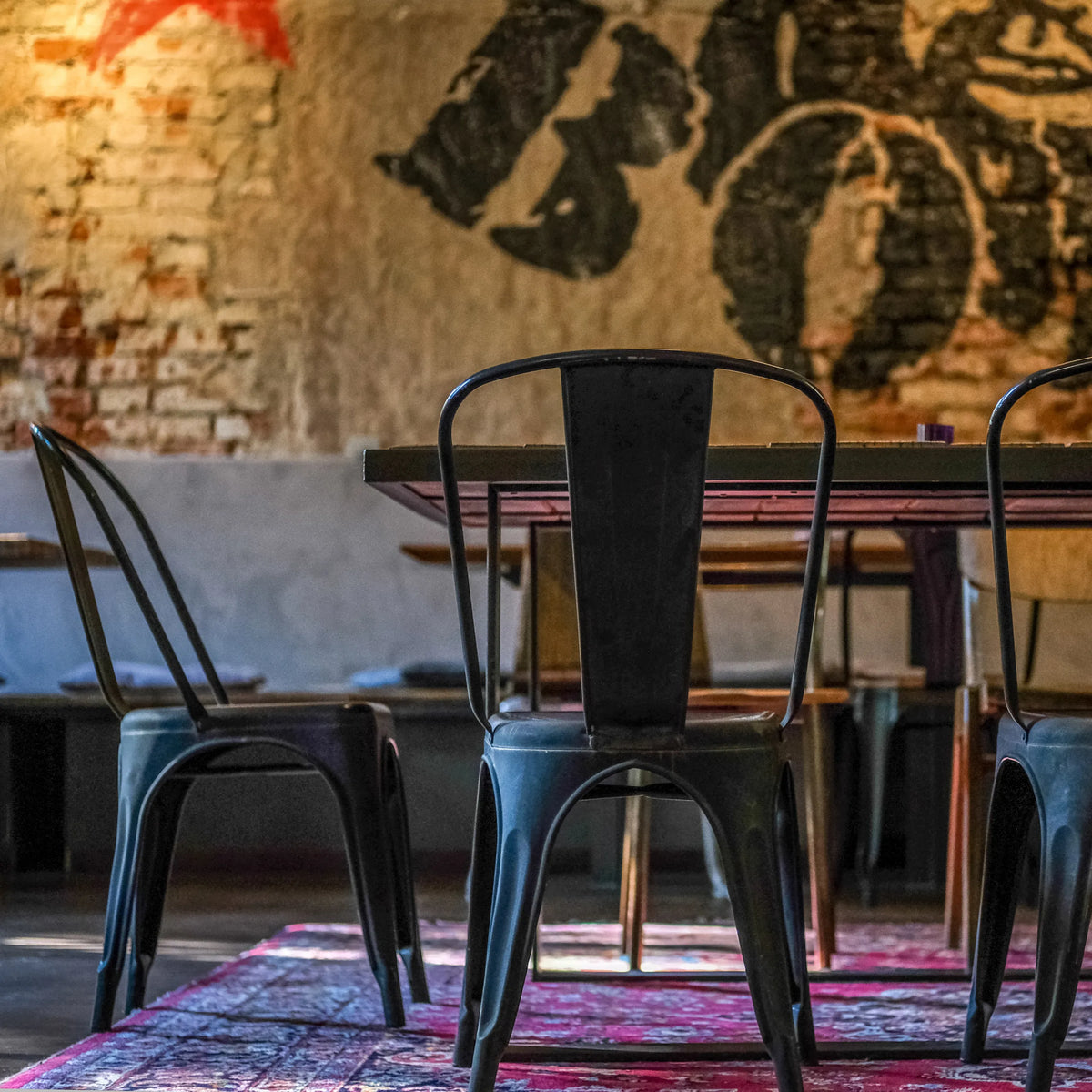 Achterzijde van een zwarte metalen VANTAGGIO BRUSH bistrostoel aan een tafel van hjh OFFICE