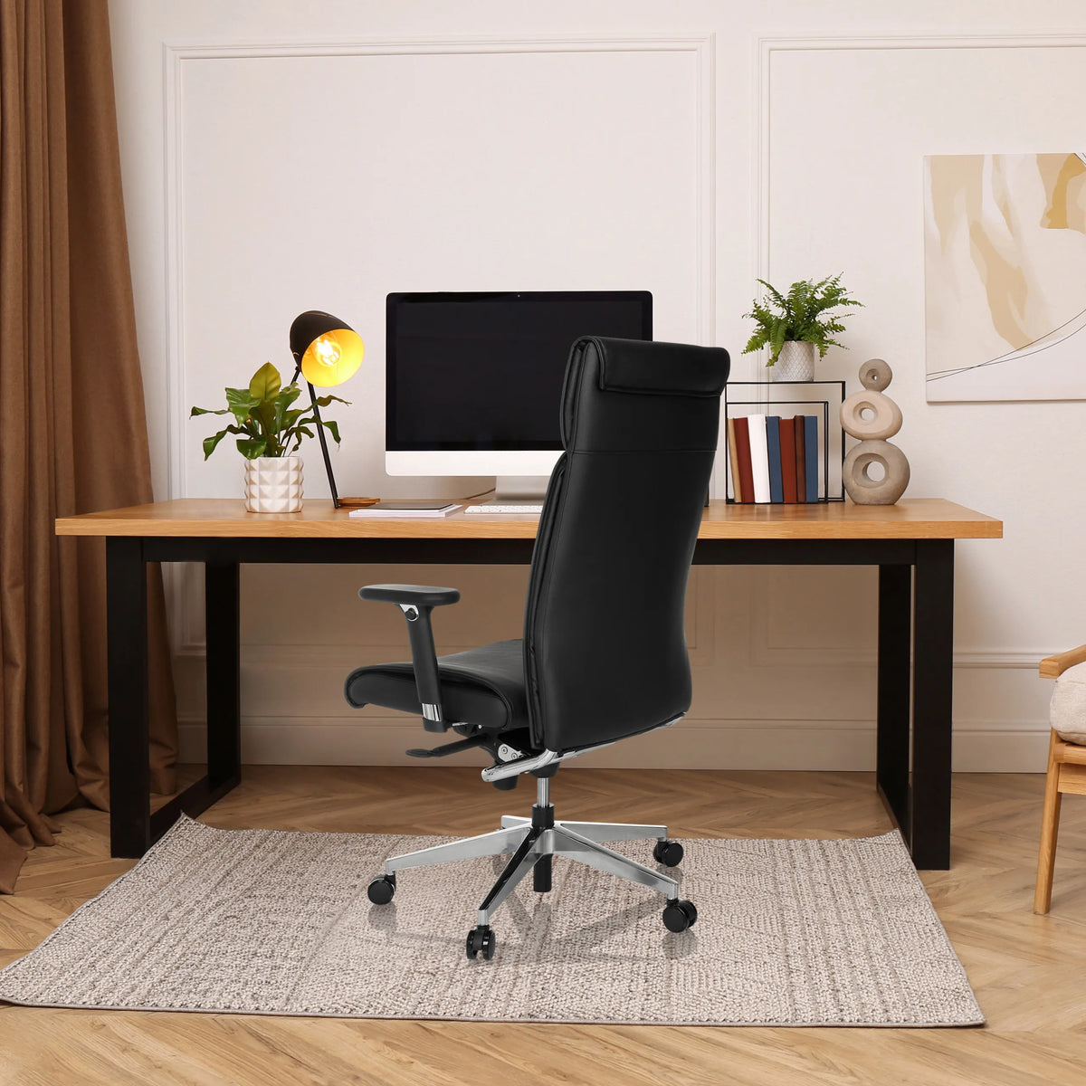 Zwarte professionele directiestoel CURYO met hoofdsteun en armleuningen aan een bureau in een thuiskantoor van hjh OFFICE