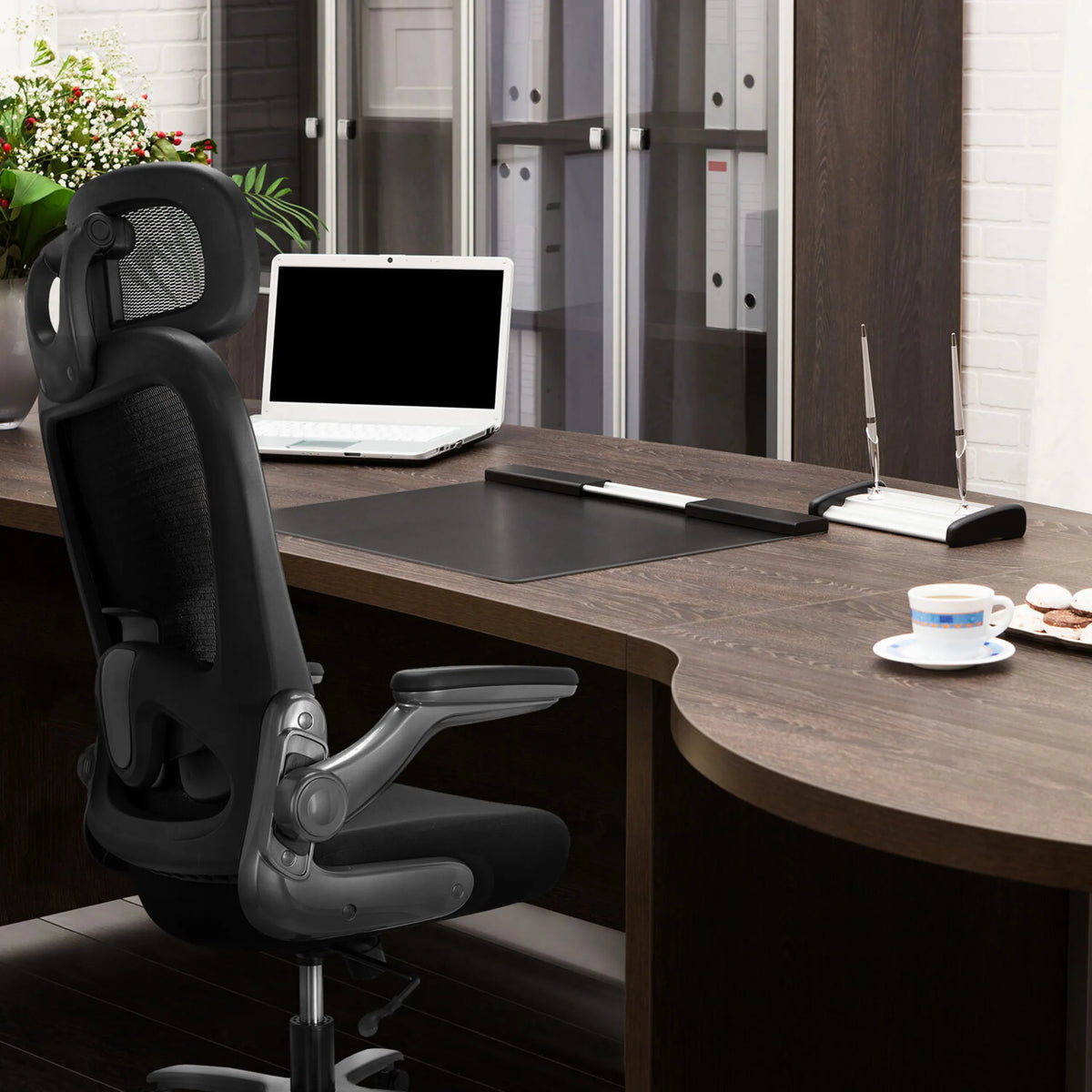 XXL bureaustoel INSTRUCTOR T I PRO in het zwart met netrugleuning aan een donker bureau van hjh OFFICE
