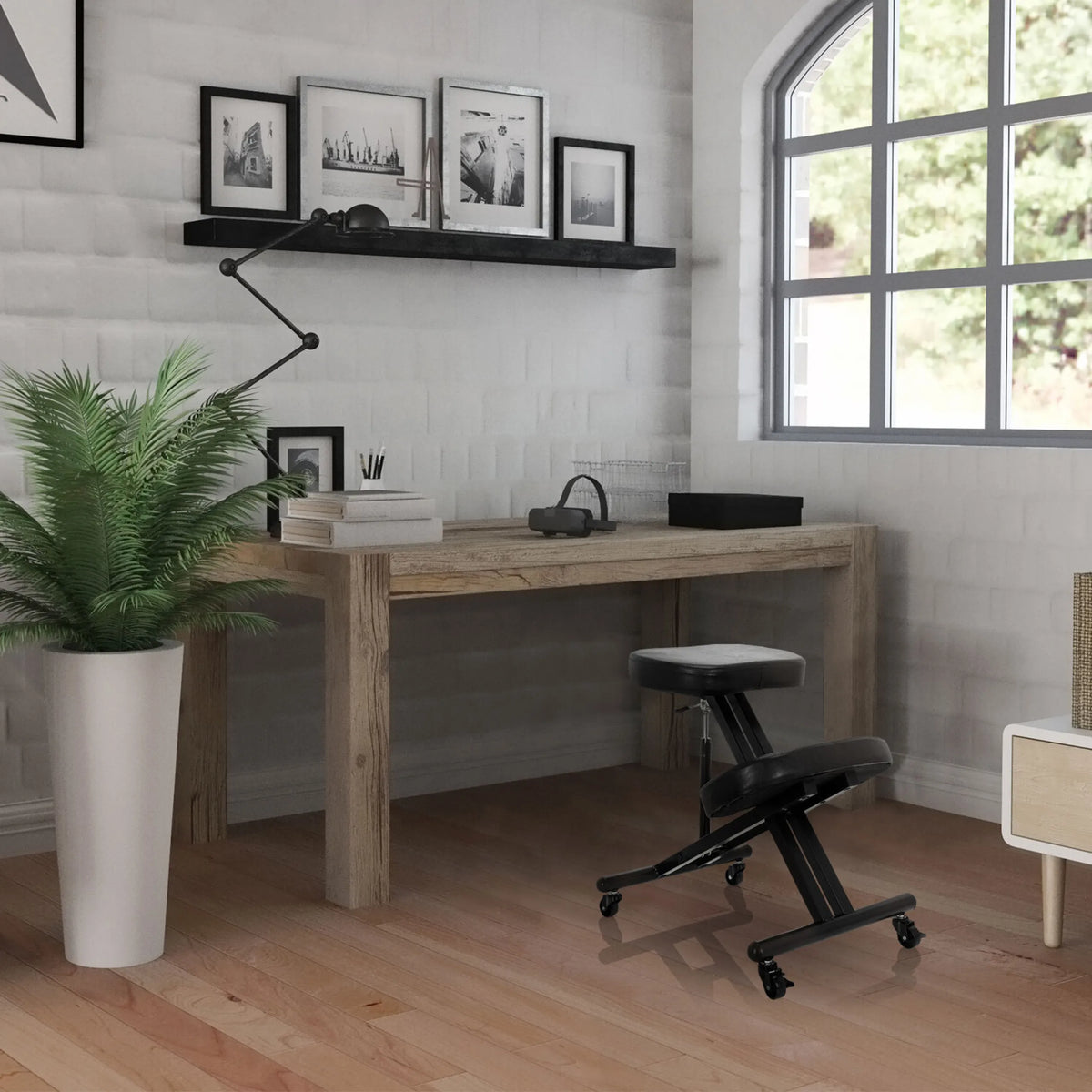 Zwarte ORTHONI kniekruk op wieltjes voor een houten bureau in een lichte kamer van hjh OFFICE