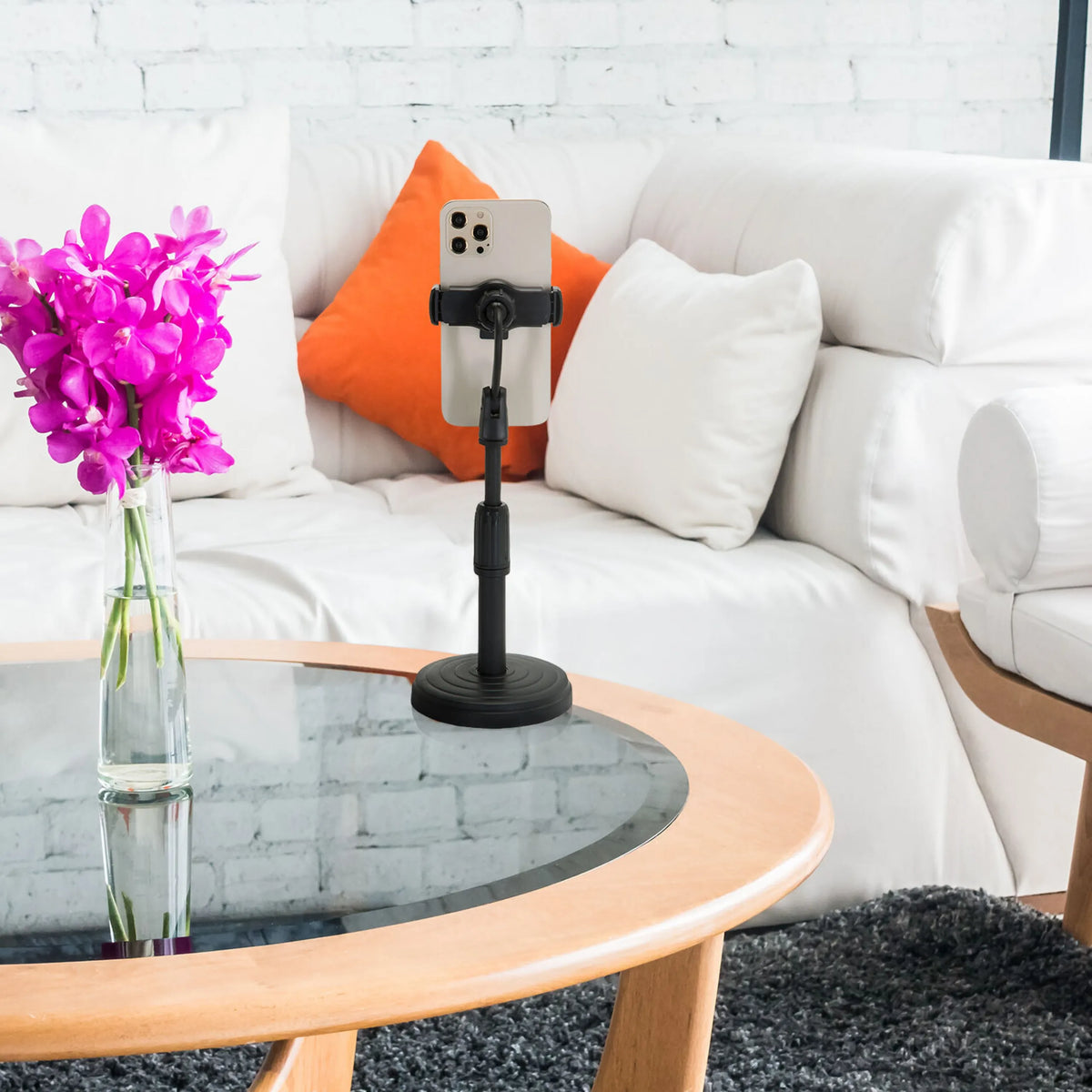 Zwarte houder voor mobiele telefoon & tablet FLEXMOBI II met smartphone op een glazen tafel voor een witte bank van hjh OFFICE
