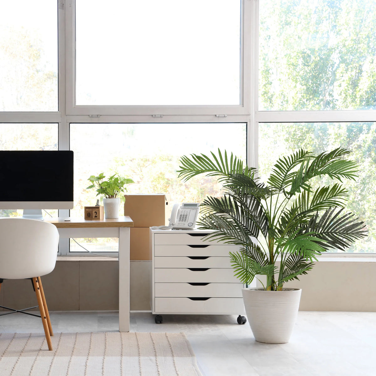Groene kunstplant ARECA II in een witte overpot naast een witte rolcontainer van hjh OFFICE