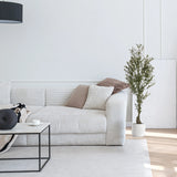 Groene kunstplant OLIVE I in een witte pot naast een lichte bank van hjh OFFICE