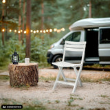 Witte TRAVANO outdoor stoel in een bosrijke omgeving naast een camper van hjh LIVING (AI-gegenereerde afbeelding)
