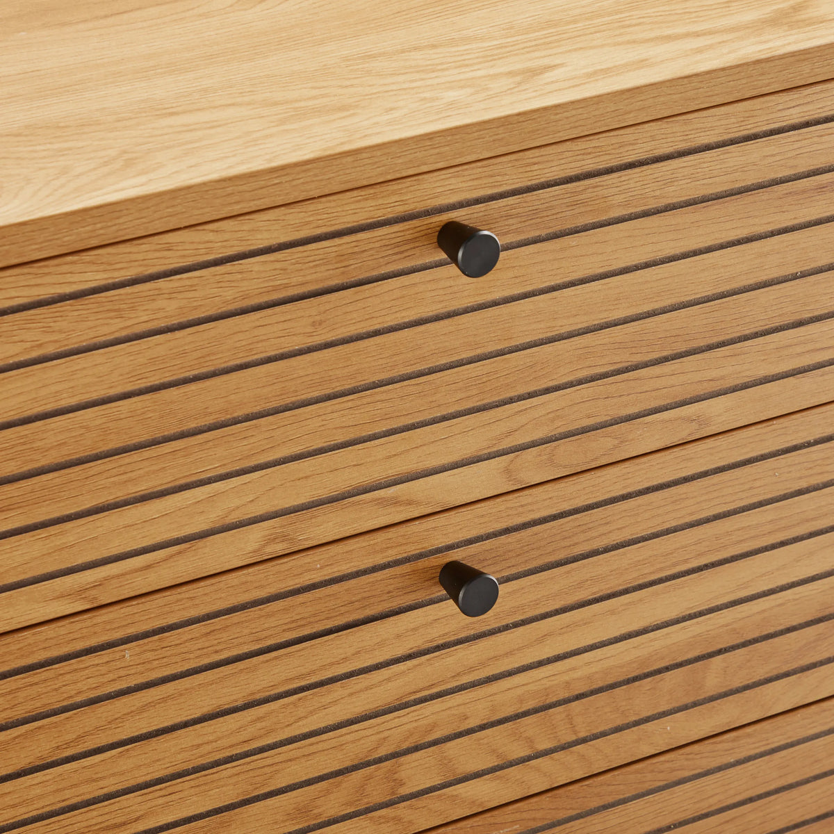 Gegroefde ladefronten met zwarte knoppen van de Commode LINNO K in eiken van hjh LIVING