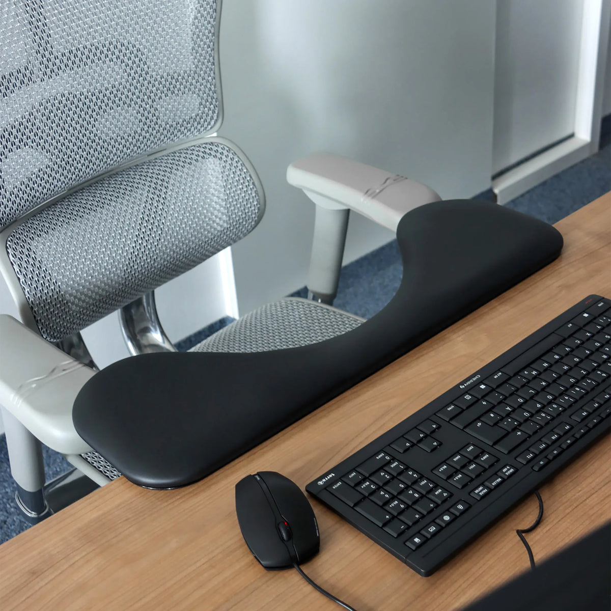 Zwarte RELEX RT2 armleuning op een bureau naast een toetsenbord en een computermuis van hjh OFFICE