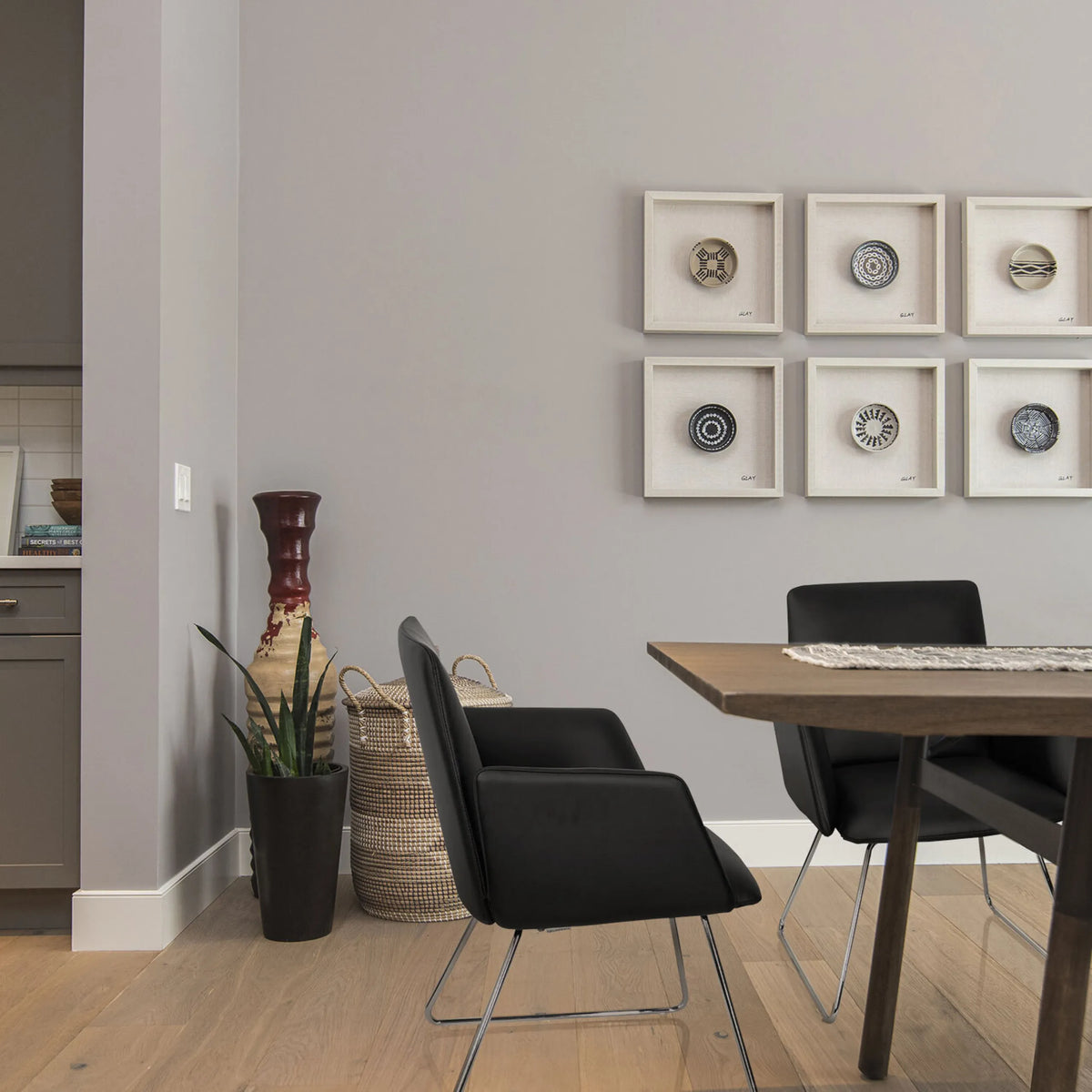 Zwarte gestoffeerde stoel DESIGNIA V met slanke metalen poten aan een houten tafel van hjh OFFICE