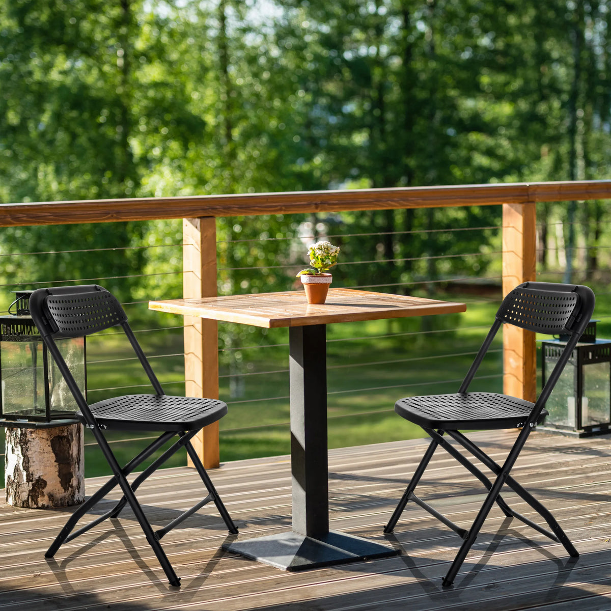 Twee zwarte Outdoor stoelen TUDELA XXL PRO met geperforeerd zitvlak aan een houten tafel van hjh OFFICE