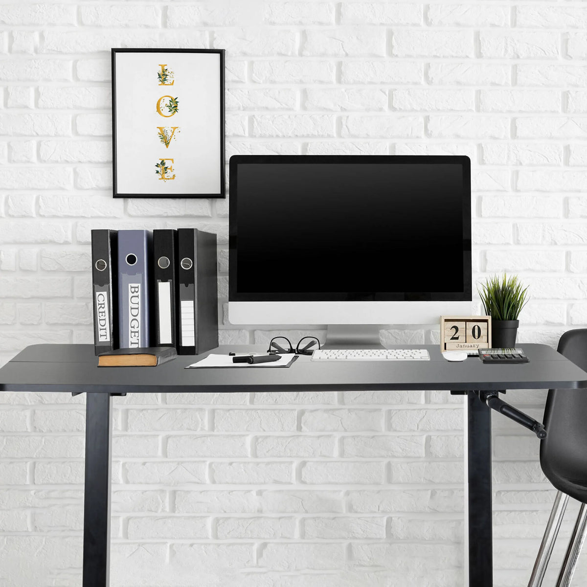 Zwart zit-sta bureau STAND CR met monitor, toetsenbord en ordners voor een witte bakstenen muur van hjh OFFICE
