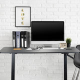 Zwart zit-sta bureau STAND CR met monitor, toetsenbord en ordners voor een witte bakstenen muur van hjh OFFICE