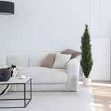Groene kunstplant CEDRUS in een witte pot naast een witte bank van hjh OFFICE