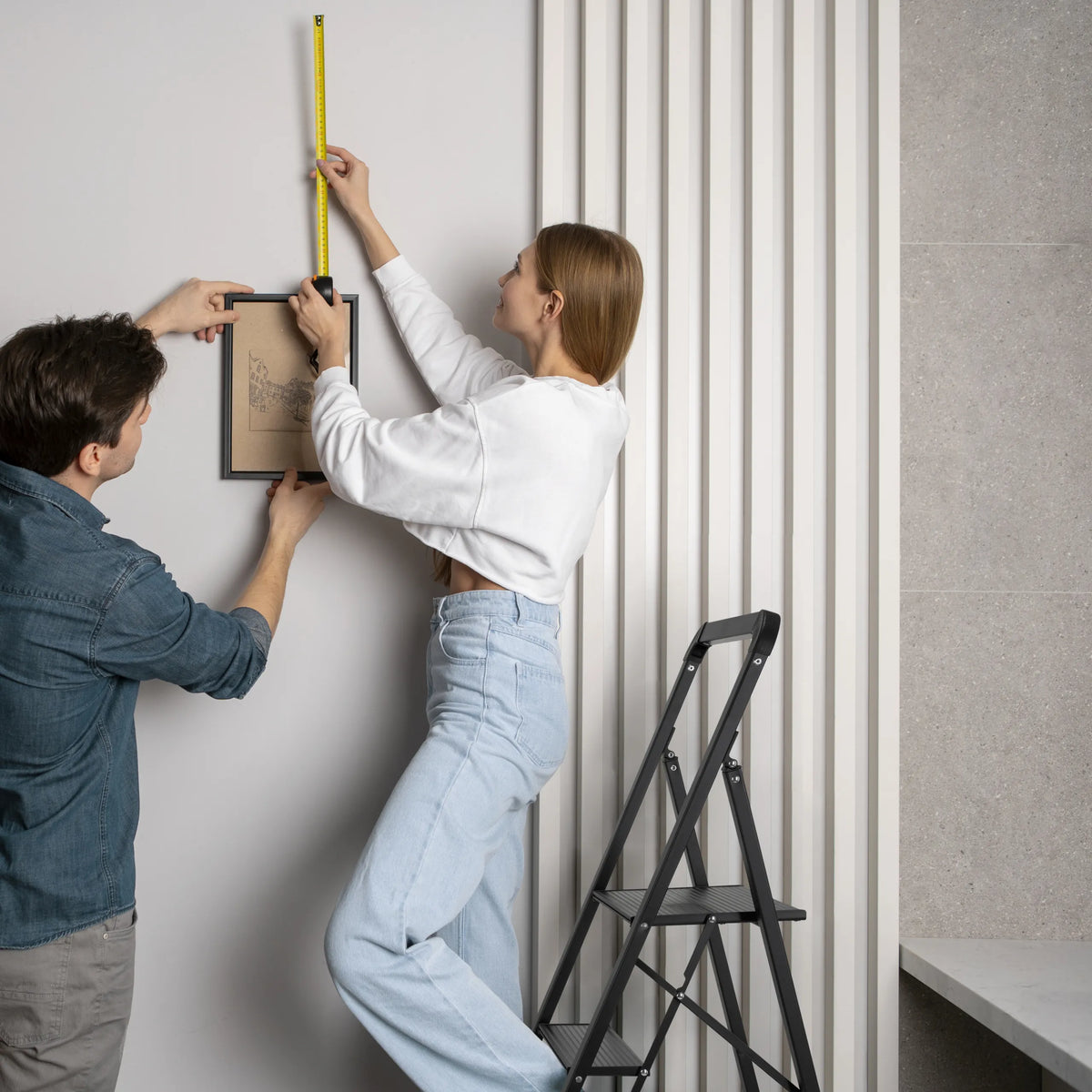 Zwarte Klaptrap SOLID W6 met drie treden in gebruik bij het ophangen van een schilderij van hjh OFFICE
