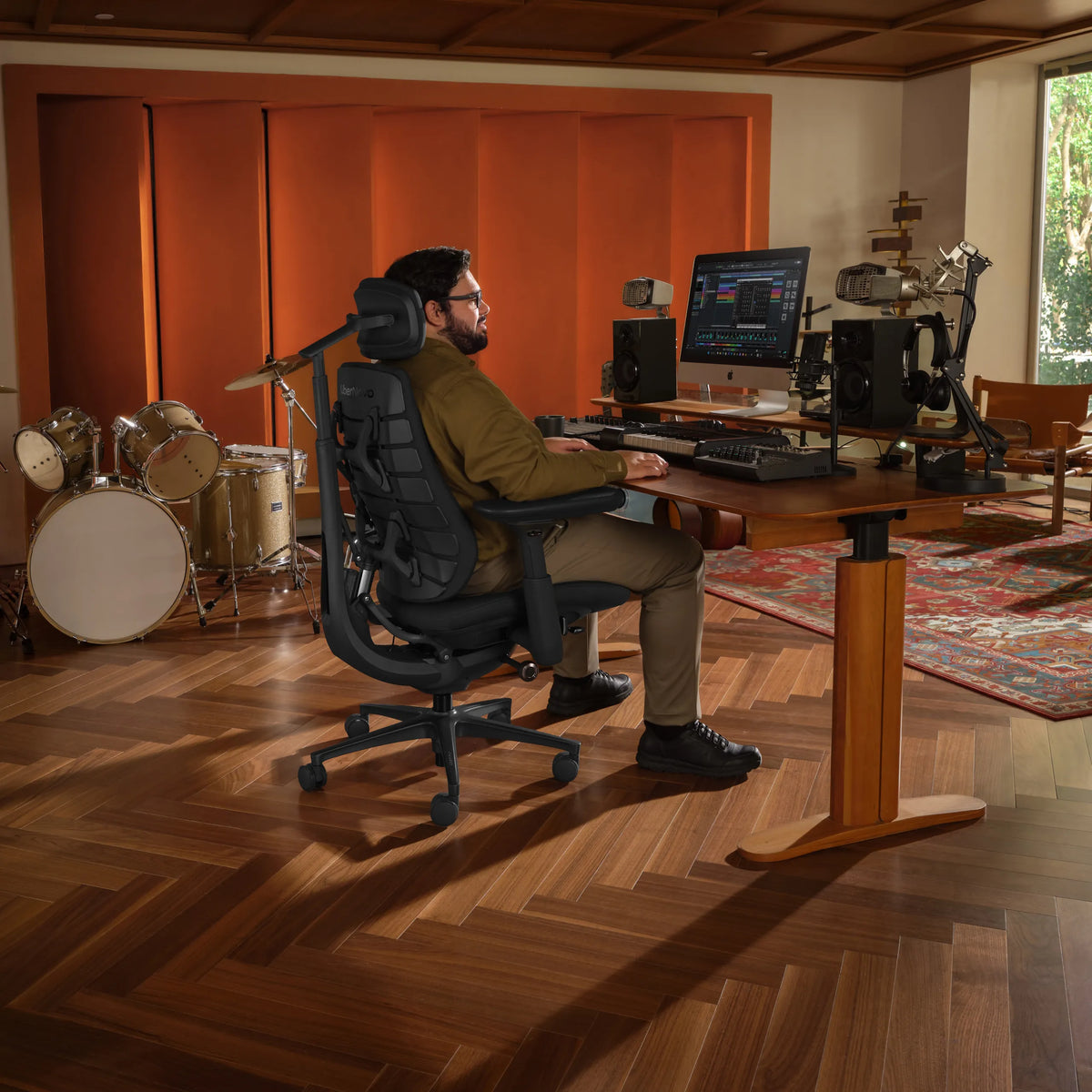 Kantoorstoel LiberNovo Maxis Airflow in grafiet aan een in hoogte verstelbaar bureau in een muziekstudio van Libernovo