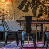 Achterzijde van een zwarte metalen VANTAGGIO BRUSH bistrostoel aan een tafel van hjh OFFICE
