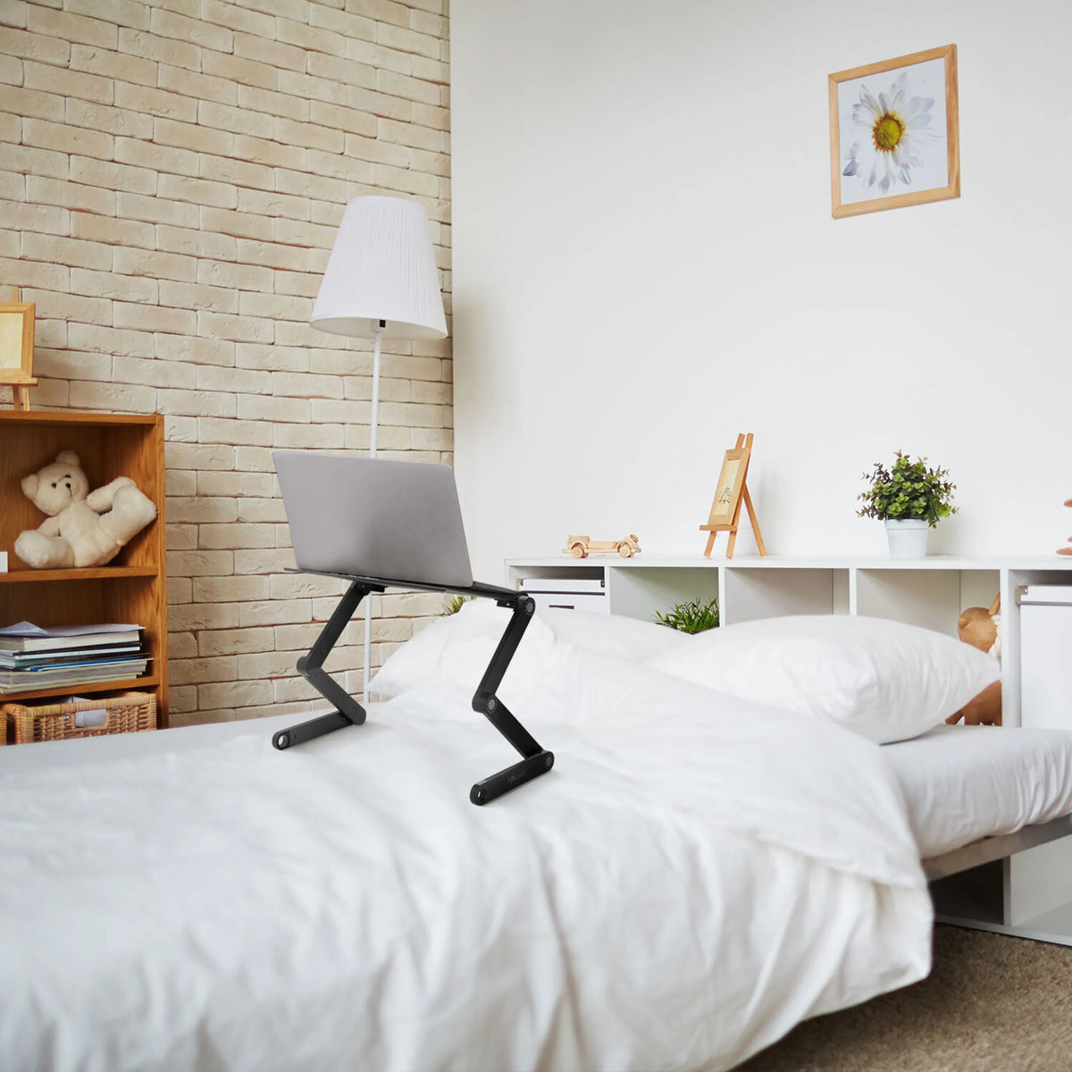 Zwarte VM-SA II monitorstandaard met laptop op een bed in een lichte kamer van hjh OFFICE
