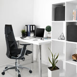 Zwarte High end bureaustoel GENIDIA met netrugleuning aan een wit bureau van hjh OFFICE
