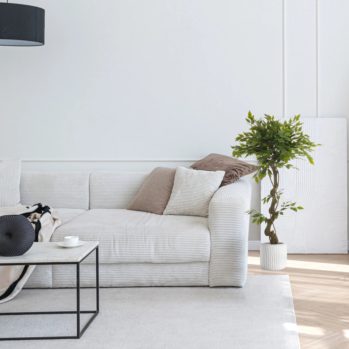 Groene kunstplant FICUS I in een witte pot naast een bank van hjh OFFICE