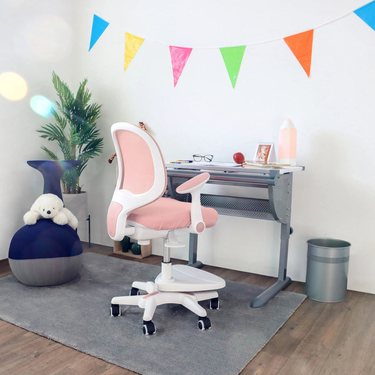 Roze kinderstoel KID ERGO met witte armleuningen en wieltjes aan een bureau van hjh OFFICE