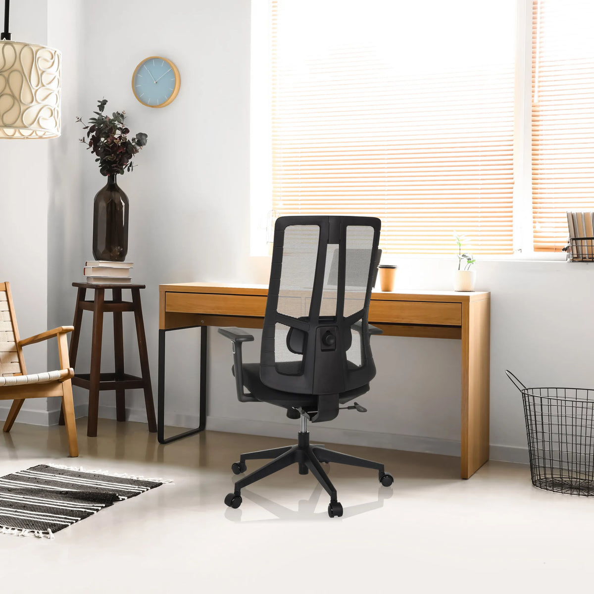 Zwarte professionele bureaustoel TRAMORE BASE met netrugleuning aan een houten bureau van hjh OFFICE