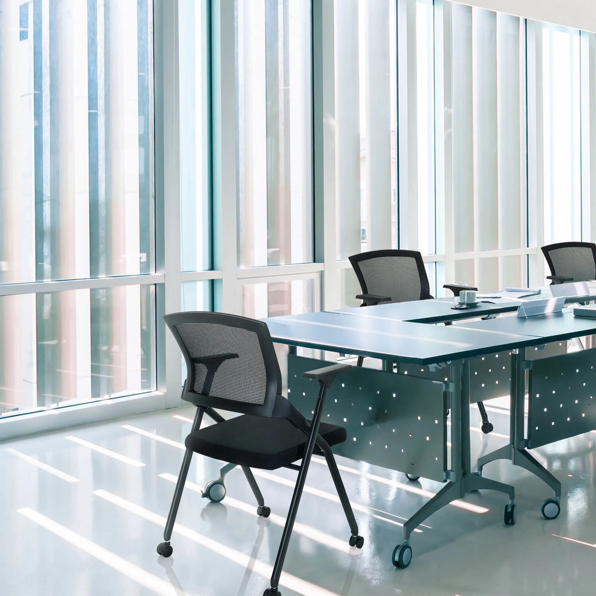 Klapstoel PRIORITY II in zwart met netbespannen rugleuning aan een conferentietafel van hjh OFFICE
