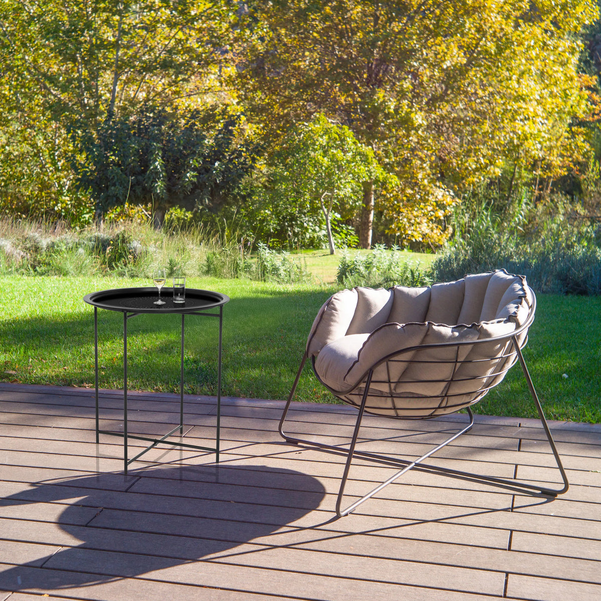 Zwarte metalen bijzettafel ALLRUND met gaatjespatroon op een terras naast een loungestoel van hjh LIVING