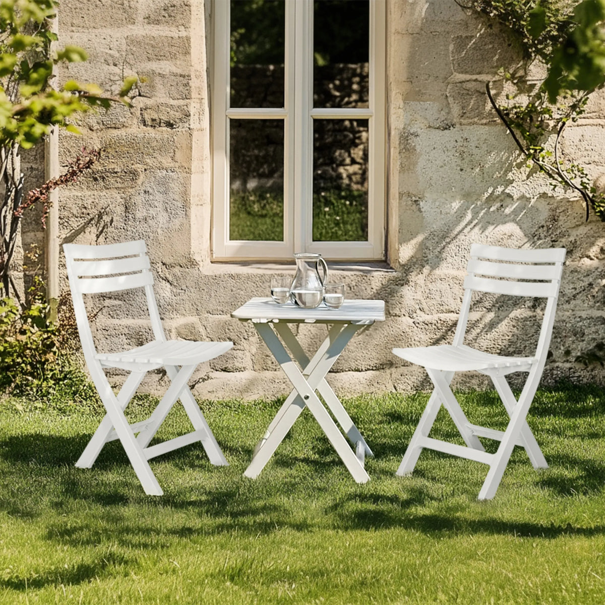 Twee witte Outdoor stoelen TRAVANO met bijpassende klaptafel op een grasveld van hjh LIVING
