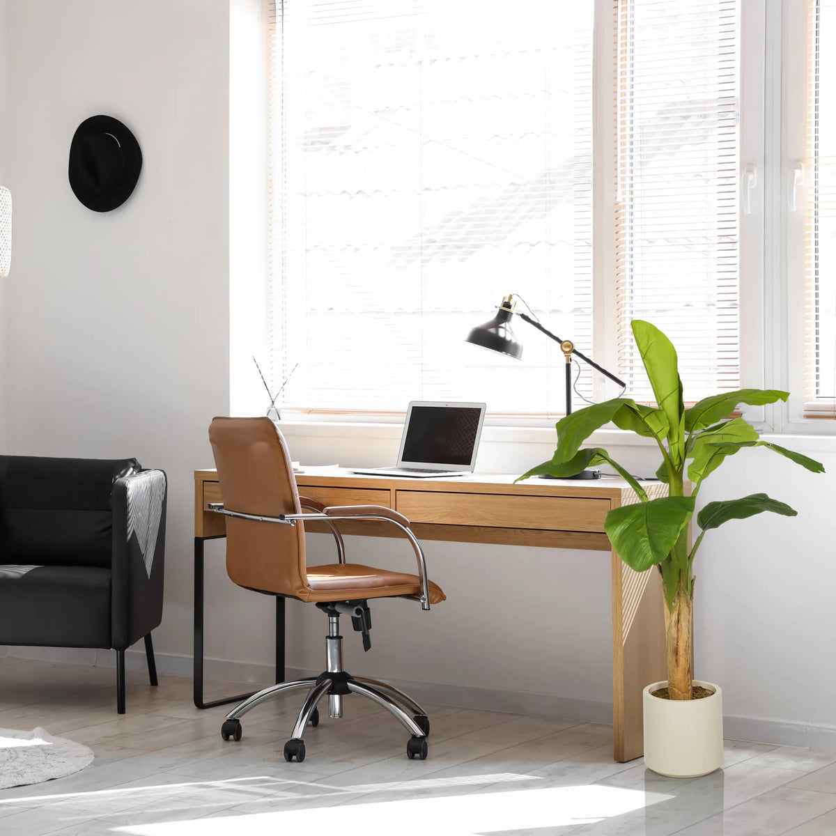 Groene kunstplant BANANE I in een lichte pot naast een bureau van hjh OFFICE